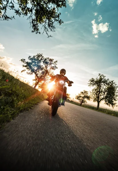 Hombre montando motocicleta deportiva durante la puesta del sol . — Foto de Stock