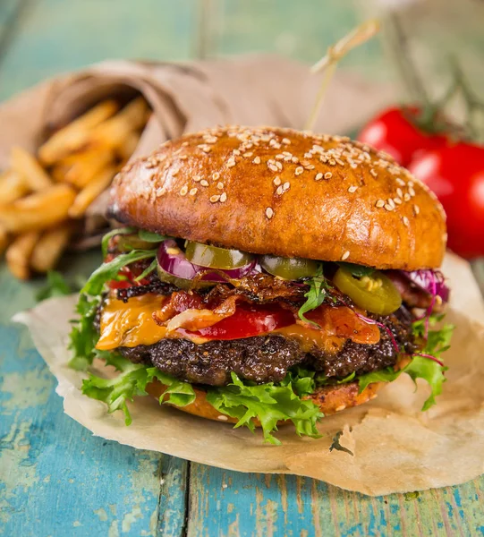 Grande hambúrguer saboroso servido na velha mesa de madeira . — Fotografia de Stock