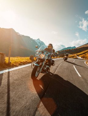 Motorcycle driver riding japanese high power cruiser in Alpine highway on famous Hochalpenstrasse, Austria. clipart