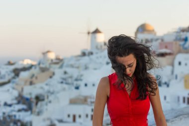 Santorini seyahat ediyor. Kırmızı elbiseli esmer kadın ünlü beyaz Oia köyünü ziyaret ediyor..