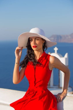Santorini seyahat ediyor. Kırmızı elbiseli esmer kadın ünlü beyaz Oia köyünü ziyaret ediyor..