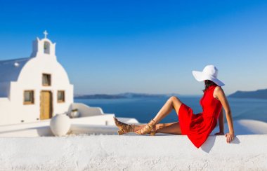 Santorini seyahat ediyor. Kırmızı elbiseli esmer kadın ünlü beyaz Oia köyünü ziyaret ediyor..