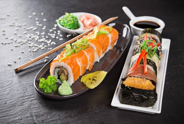 Sushi japonés ambientado sobre un fondo rústico oscuro . — Foto de Stock