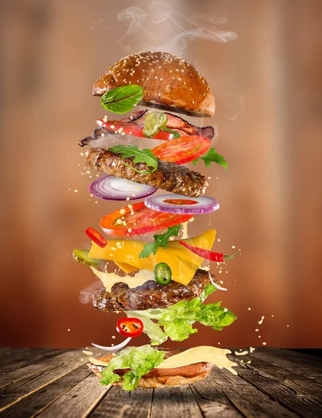 Big gustoso hamburger con ingredienti volanti . — Foto Stock