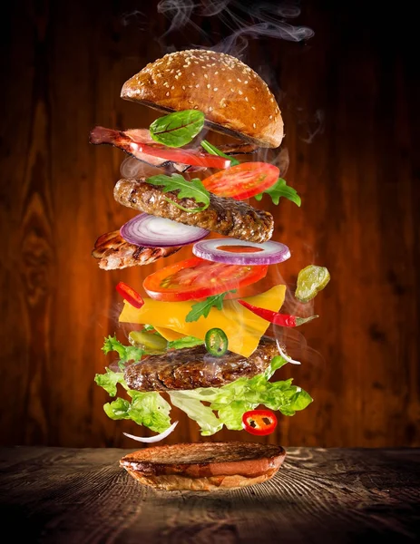 Big gustoso hamburger con ingredienti volanti . — Foto Stock