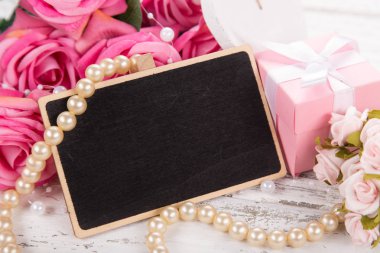 Sevgililer Günü ya da Anneler Günü için küçük bir yazı tahtası. Pembe güllerle arka plan.