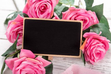 Sevgililer Günü ya da Anneler Günü için küçük bir yazı tahtası. Pembe güllerle arka plan.