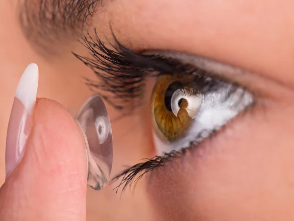 Young woman putting contact lens in her eye. — Stock Photo, Image