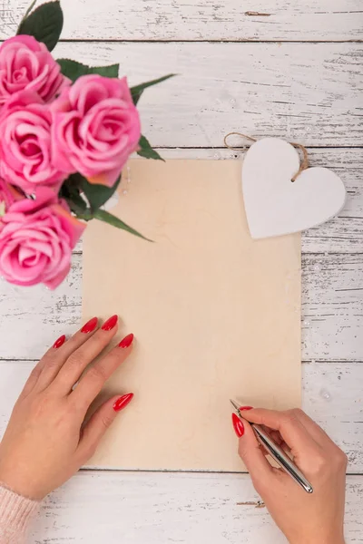 Papel en blanco vacío con manos de mujer. Fondo con rosas rosadas en jarrón . —  Fotos de Stock