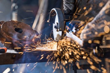 Öğütücüyle metal kesen bir işçi.