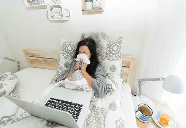 Young woman having flu, blowing her nose.