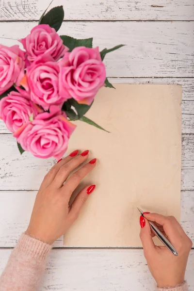 Papel en blanco vacío con manos de mujer. Fondo con rosas rosadas en jarrón . —  Fotos de Stock