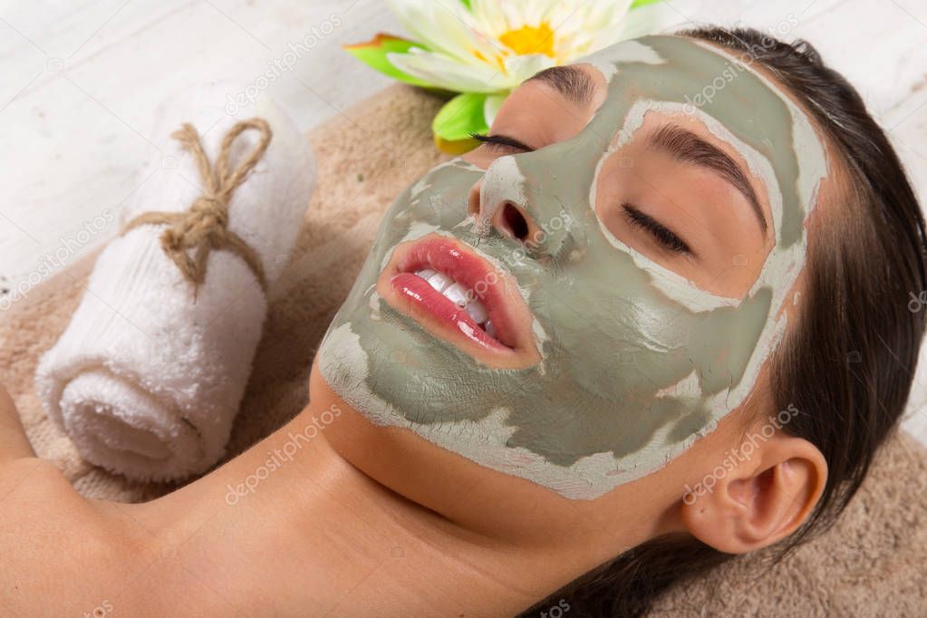 Young healthy woman with face clay mask.