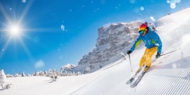 Kayakçı yokuş aşağı güzel Alp manzara modunda çalışan pist üzerinde. Zemin üzerine mavi gökyüzü.