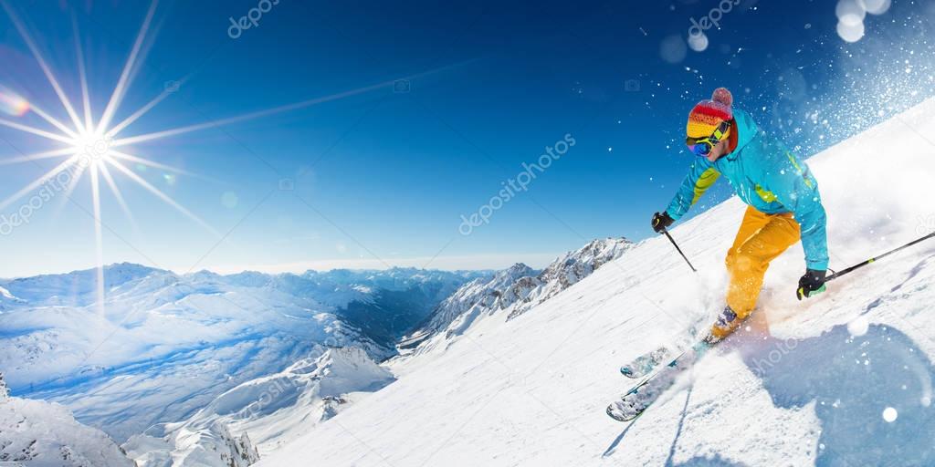 Skier on piste running downhill in beautiful Alpine landscape. Blue sky on background.