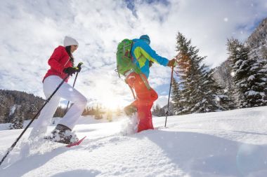 Snowshoe walkers running in powder snow with beautiful sunrise light. clipart