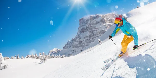 Skifahrer auf der abschüssigen Piste in wunderschöner alpiner Landschaft. blauer Himmel auf Hintergrund. — Stockfoto