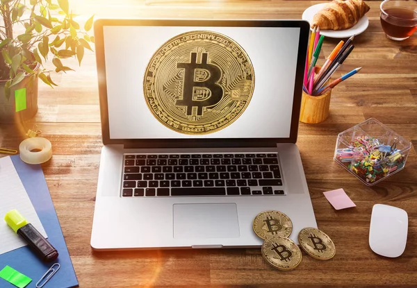 Bitcoin-Goldmünze mit Laptop auf Holztisch im Büro. — Stockfoto