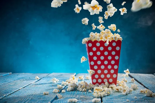 Doos van popcorn op blauwe achtergrond. — Stockfoto