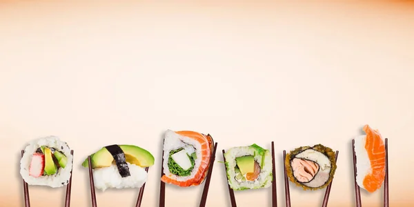 Traditional japanese sushi pieces placed between chopsticks on pastel color background. — Stock Photo, Image