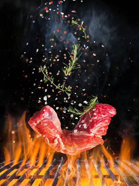 Raw beef steak flying above hot grill grate with flames. — Stock Photo, Image