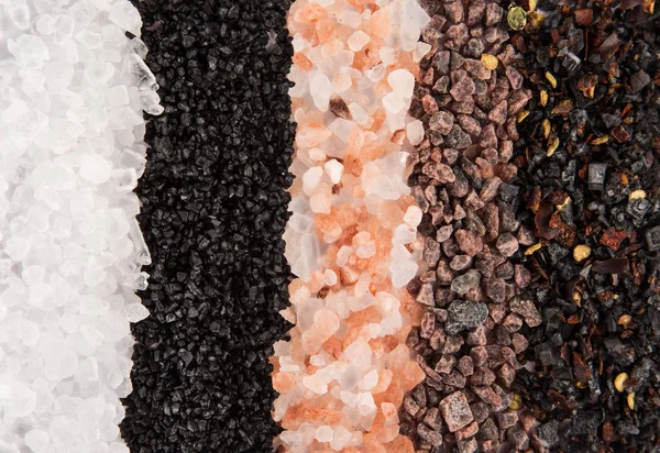 Verschiedene grobkörnige Salze auf schwarzem Steinhintergrund. — Stockfoto