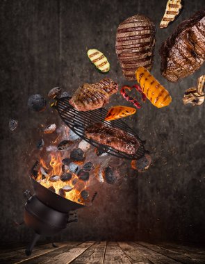 Su ısıtıcısı ızgara sıcak briketler, dökme demir ızgara ve havada uçan lezzetli sığır eti biftek.