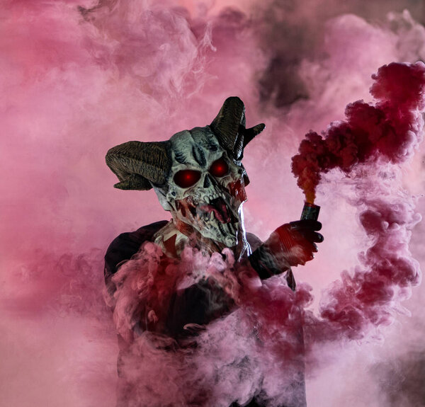 guy in devil mask standing with smoke bombs