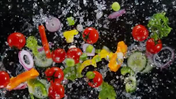 Frisches Gemüse mit Wassertropfen, die auf schwarzem Hintergrund explodieren. — Stockvideo