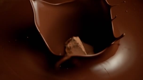 Супер повільний рух літаючих сирих шматочків шоколаду в розплавлений шоколад . — стокове відео
