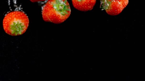 Εκρηκτικές φράουλες με νερό σε μαύρο φόντο. — Αρχείο Βίντεο