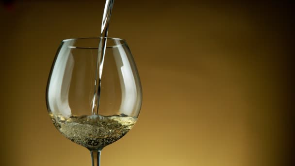 Super Slow Motion Detail shot van het gieten van witte wijn uit fles op gouden achtergrond. — Stockvideo