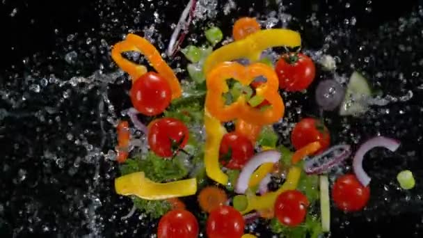 Légumes frais avec des gouttelettes d'eau explosant sur fond noir . — Video