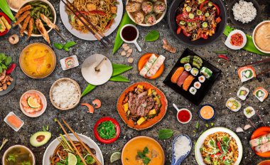 Köy taşından arka planda çeşitli malzemeler içeren Asya yemekleri, üst görünüm.