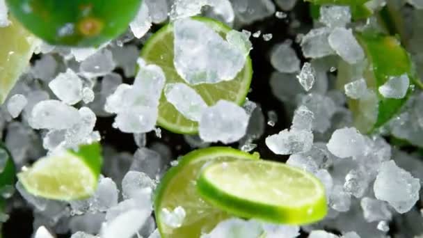 Mouvement super lent de la glace écrasée explosant avec des citrons verts vers la caméra — Video