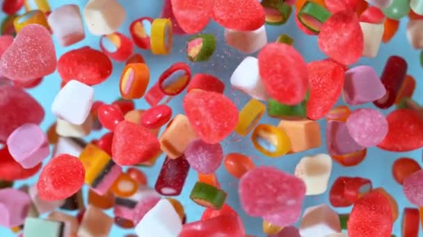 Bonbons fliegen in Zeitlupe vor pastellfarbenem Hintergrund — Stockvideo