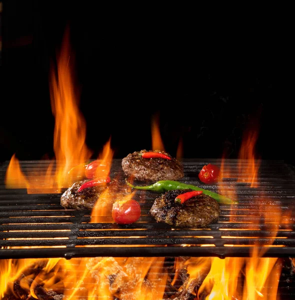 Tasty beef steaks flying above cast iron grate with fire flames. — Stock Photo, Image