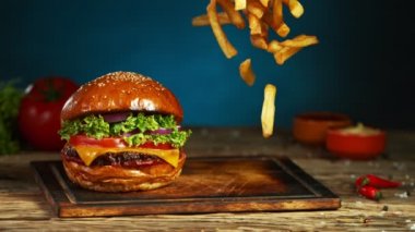 Patates kızartması çizburgerin yanına düşer ve eski ahşap kesme tahtasının üzerine yatar. Süper Yavaş Çekim