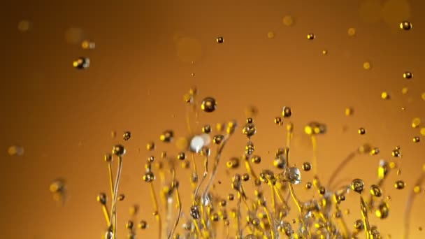 Super ralenti prise de vue de l'huile éclaboussante sur fond doré à 1000fps.