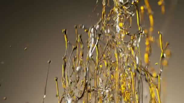 Super ralenti prise de vue de l'huile éclaboussante sur fond doré à 1000fps.