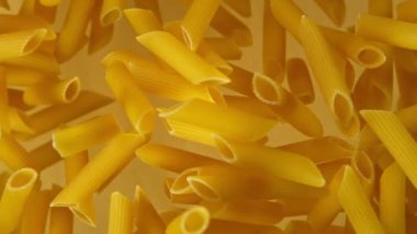 Altın arka planda pişirilmemiş İtalyan makarnasının süper yavaş çekimi..