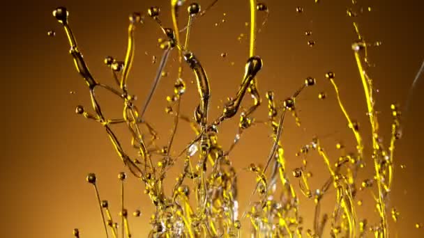 Super ralenti prise de vue de l'huile éclaboussante sur fond doré à 1000fps.