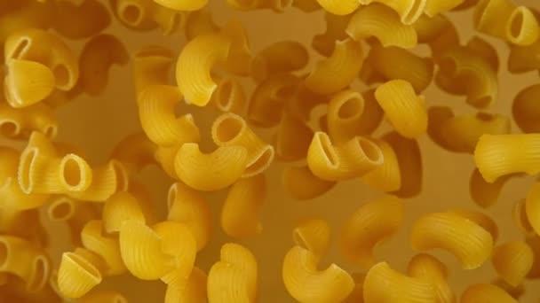 Super cámara lenta de la pasta italiana volando sin cocer sobre fondo dorado. — Vídeos de Stock