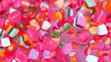 Pastel arka planda yavaş çekimde uçuşan tatlı şekerler. Yüksek hızlı sinema kamerasıyla çekilmiş.