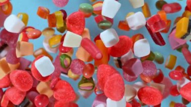 Pastel arka planda yavaş çekimde uçuşan tatlı şekerler. Yüksek hızlı sinema kamerasıyla çekilmiş.