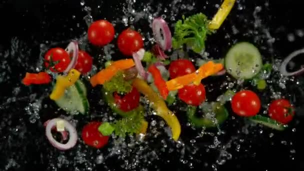 Légumes frais avec des gouttelettes d'eau explosant sur fond noir . — Video