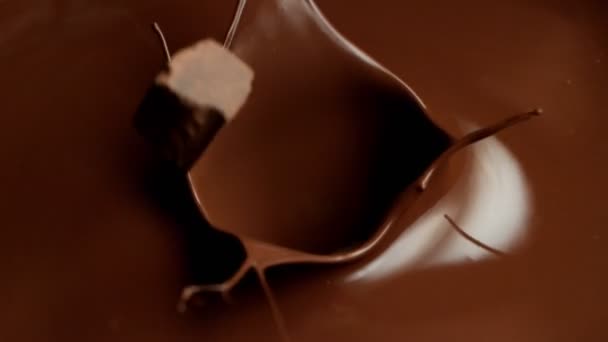 Super slow motion of flying raw chocolate pieces splashing into molten chocolate. — Stock Video