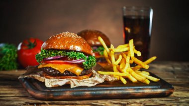 Patates kızartması çizburgerin yanına düşer, eski ahşap kesim tahtasının üzerine uzanır..