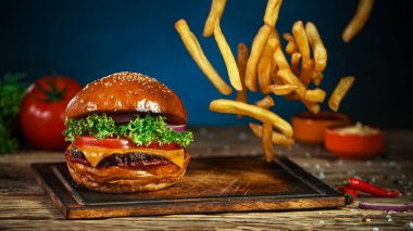 Patates kızartması çizburgerin yanına düşer, eski ahşap kesim tahtasının üzerine uzanır..