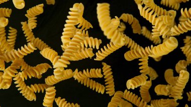 Siyah zemin üzerinde pişirilmemiş İtalyan makarnasının dondurucu hareketi.